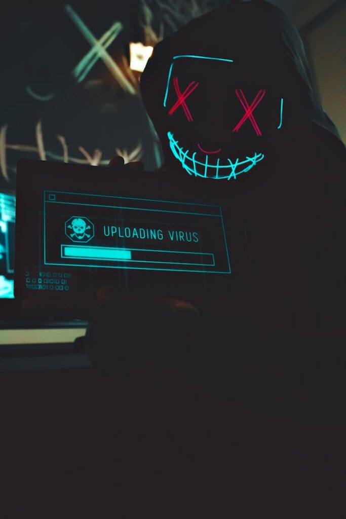 Hacker wearing a glowing neon mask holding a digital tablet displaying a virus upload.